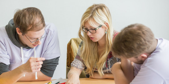 Math Helpdesk Three people are sitting at a table and learning.